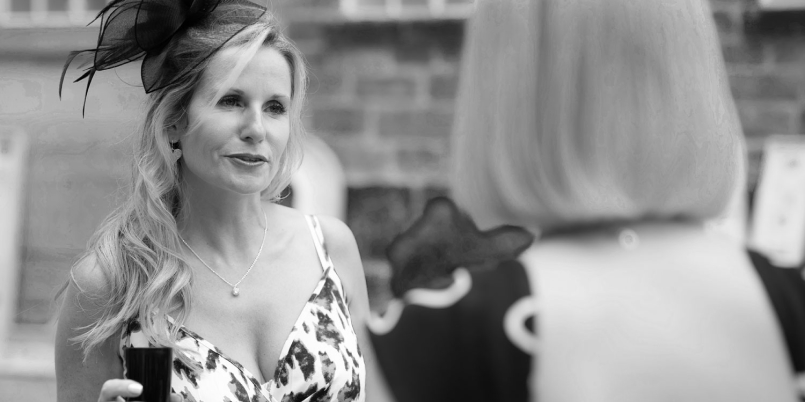 Lloyd Dunkley Photography, At the wedding, a beautiful young woman in an elegant dress and fascinator enjoys a drink.
