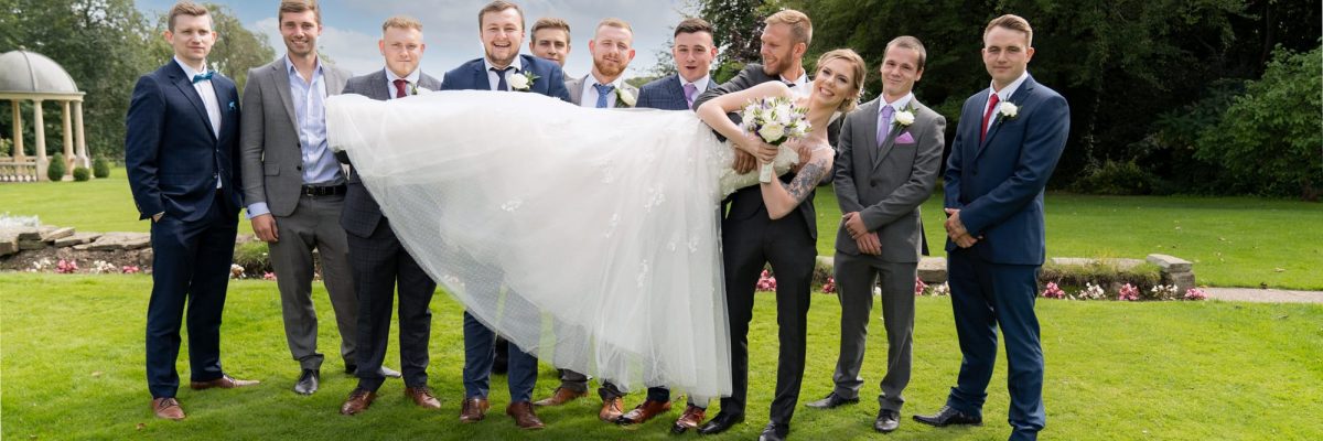Fun, picture of the bride bean held horizontally with a bouquet by the groomsmen.